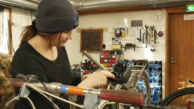 Rosa purkamassa polkupyörää pyöräkorjaamon pajalla.