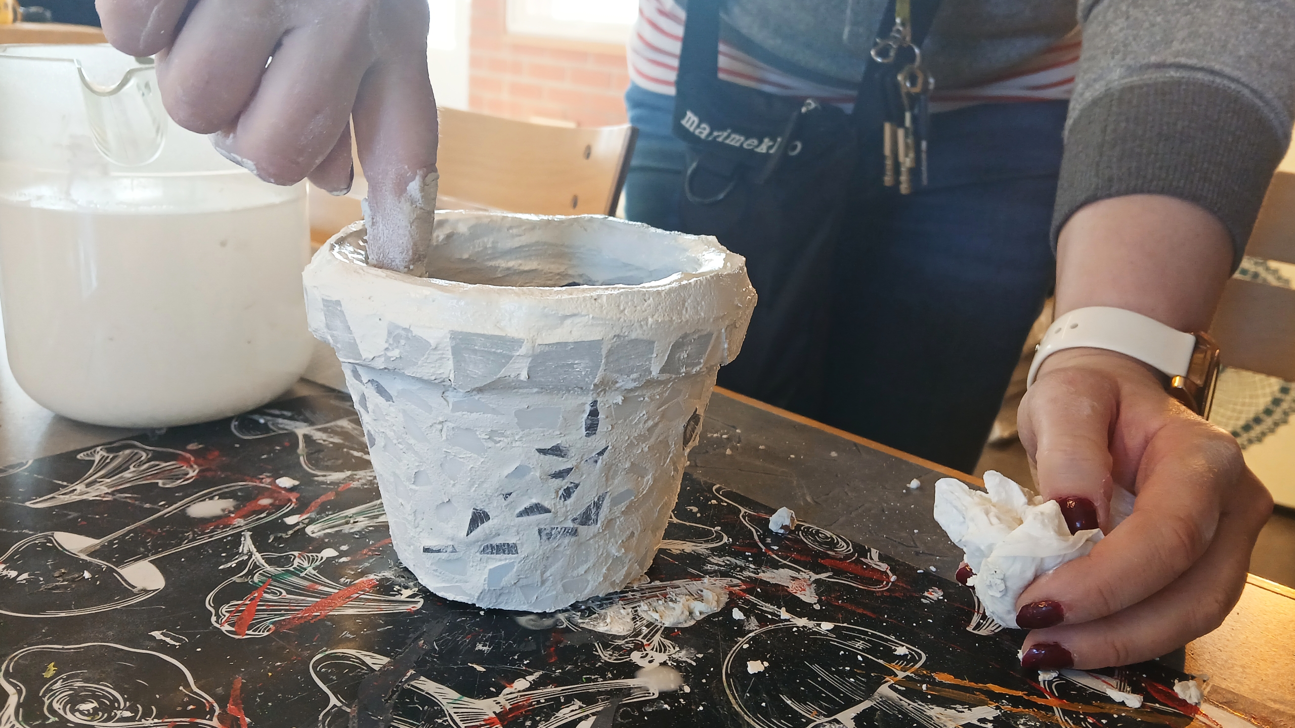 Rosalie tasoittaa sormellaan ruukun sisäpintaan levitettyä liimaa.