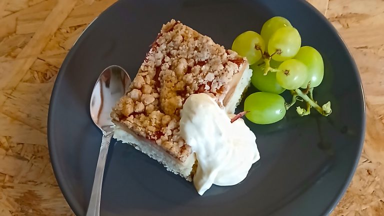 Ideapajassa tarjoiltu jälkiruoka. Lautasella on lusikka, kermavaahdolla koristeltu piirakanpalanen, sekä pieni viinirypäleterttu.