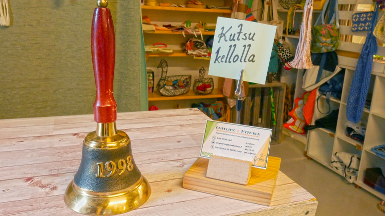 Myyntitiskin päällä on vanhanaikainen varrellinen soittokello, jonka metalliosassa lukee "1998". Kellon vieressä on käyntikorttiteline, jossa on myymälän yhteystiedot sisältäviä käyntikortteja. Tiskillä on myös lappu joka kehoittaa "Kutsu kellolla".