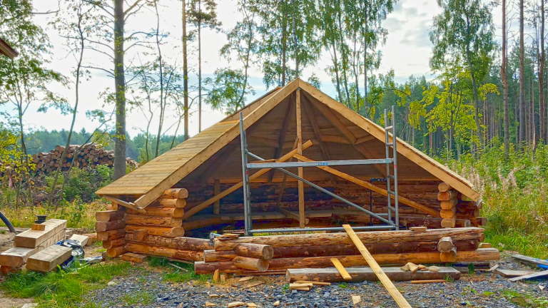 Rakenteilla oleva puinen kota keskellä Hietasaaren luontomaisemaa.