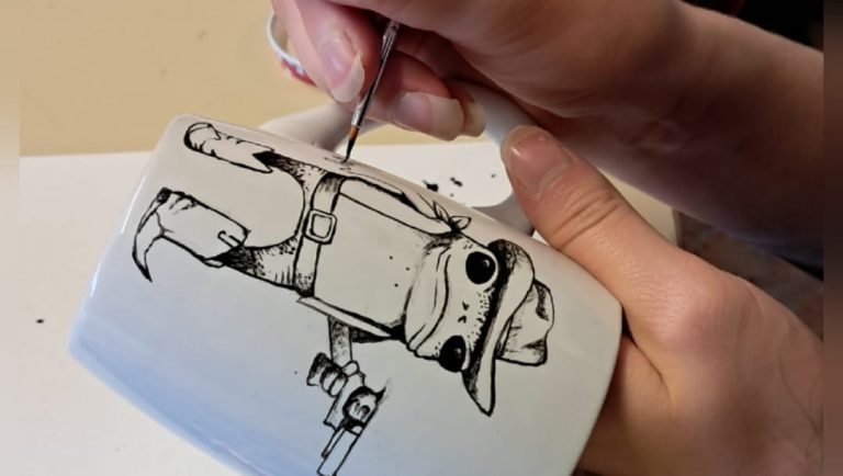 Kahvimukiin ollaan maalaamassa humoristista cowboy-sammakkoa. Sammakko on seisomassa kahdella jalalla kuin ihminen, ja hänellä on päällään leveälierinen stetson-hattu, liivit, vyöllä kiinnitetyt housut ja isot nahkasaappaat. Sammakko osoittaa kädessään olevalla revolverilla sivulle.