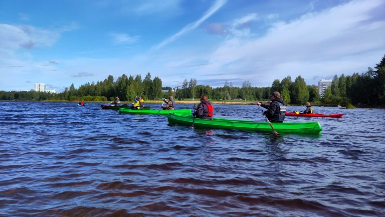 Oulun edustan vesialueilla on joukko pelastusliivit päällään olevia nuoria melomassa kanootteja.