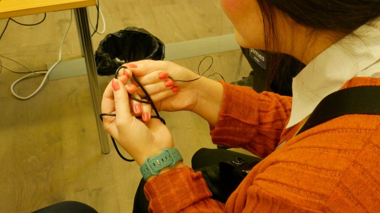 Rosalie tarkastelee kätensä ympärille kiedottua datakaapelia. Kaapeli on rikki, ja Rosalie etsii mahdollisen vian syytä.