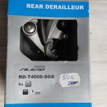 Shimano-merkkinen pyörän takavaihtaja alkuperäispakkauksessaan. Pakkauksessa lukee "Shimano rear derailleur".