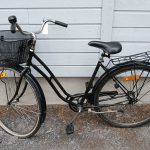 Musta 28 tuumainen Helkama Aino merkkinen naisten polkupyörä, tarakka, edessä kori, soittokello, useita heijastimia, lukko, seisontatuki.