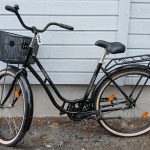 Musta 26 -tuumainen Helkama Aino -merkkinen matalarunkoinen kaupunkipyörä. Pyörässä on useita heijastimia, seisontatuki, tarakka, soittokello, edessä kori.