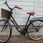 Musta 28 -tuumainen kolmi -vaihteinen Solifer Vintage -merkkinen matalarunkoinen kaupunkipyörä. Pyörässä on useita heijastimia, tarakka, punamusta soittokello, seisontatuki, käsin toimiva etujarru, ruskeapenkki, ruskeat ohjaustangon tupet, edessä ruskea punottu puinen kori, lukko.