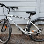 Valkoinen 21 -vaihteinen, 28 -tuumainen Spokes Roller 21 -merkkinen korkearunkoinen kaupunkipyörä. Pyörässä on käsin toimivat etu ja taka jarrut, useita heijastimia, seisontatuki, käsin säädettävä penkki, penkin takaosassa hieman halkeamia, etuhaarukka ja ohjaustanko on mustat