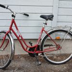 Punainen 28 -tuumainen Titania Classic -merkkinen matalarunkoinen kaupunkipyörä. Pyörässä on useita heijastimia, seisontatuki, tarakka, soittokello, kromiset lokasuojat.
