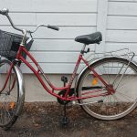 Punainen 28 -tuumainen Titania Silver Wing -merkkinen matalarunkoinen kaupunkipyörä. Pyörässä on useita heijastimia, seisontatuki, tarakka, krominen soittokello, edessä kori.